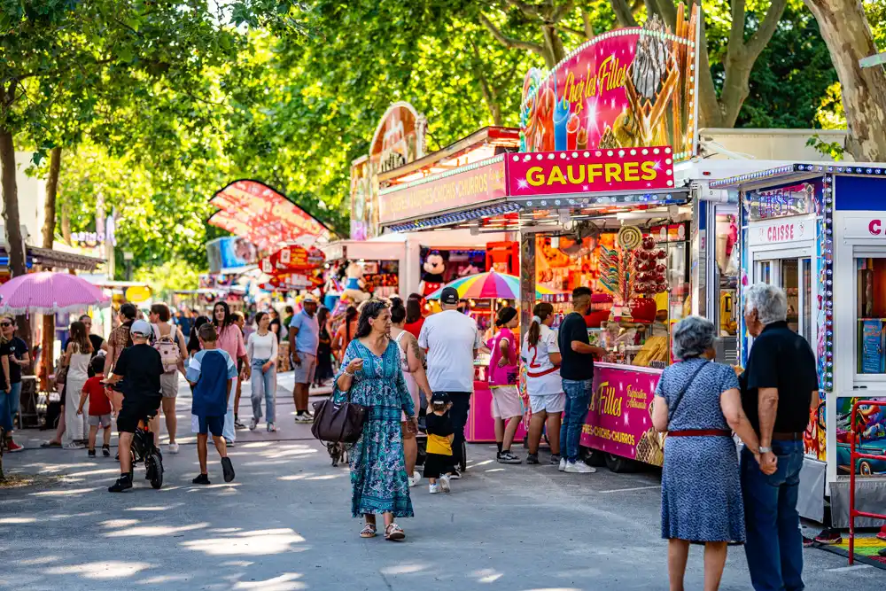 Allées d'Azémar animées par les stands et manèges de la fête foraine de la Saint-Hermentaire.