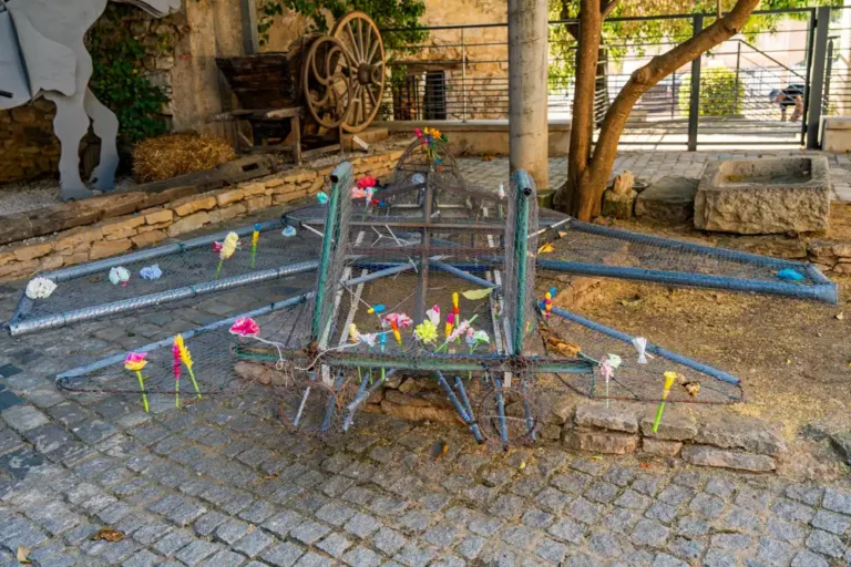 Structure métallique en forme d'avion décorée de fleurs en papier, installée au sol sur un pavage extérieur.