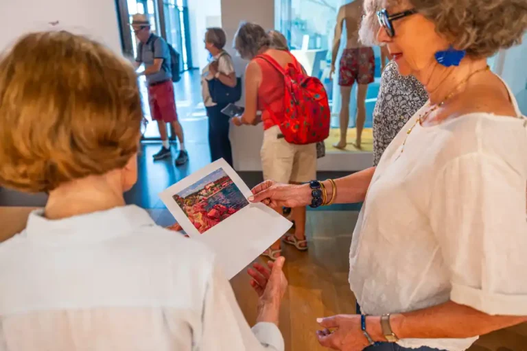 Visiteurs observant une reproduction d'œuvre picturale lors de la visite guidée de l'exposition sur l'histoire du tourisme dans le Var.