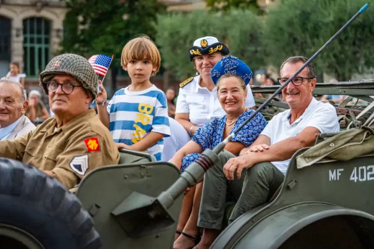 Personnes en tenue civile et militaire à bord d'une jeep d'époque lors du défilé de la Libération sur le boulevard Clemenceau.