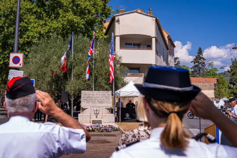 Cérémonie commémorative devant la stèle de la Libération de Draguignan, avec des représentants en uniforme saluant les drapeaux.