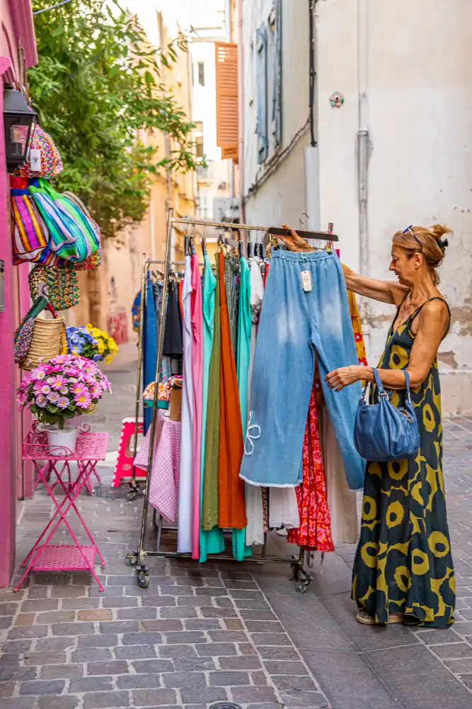 Cliente examinant des vêtements sur un portant installé dans une rue piétonne lors de la braderie des commerçants.