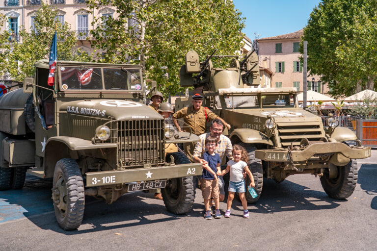Reconstitution d'un camp militaire US au jardin Anglès avec des véhicules d'époque et des figurants en tenue militaire entourés de visiteurs.