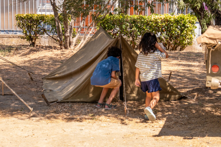 Deux enfants visitant une tente militaire lors de la reconstitution d'un camp US au jardin Anglès.