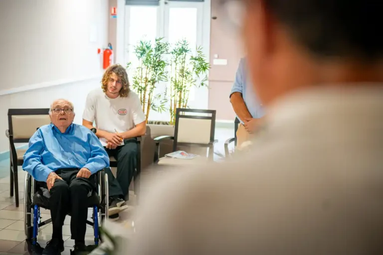 Albert Donnat assis dans un fauteuil roulant, entouré de personnes lors de la cérémonie de remise de la Légion d'honneur.