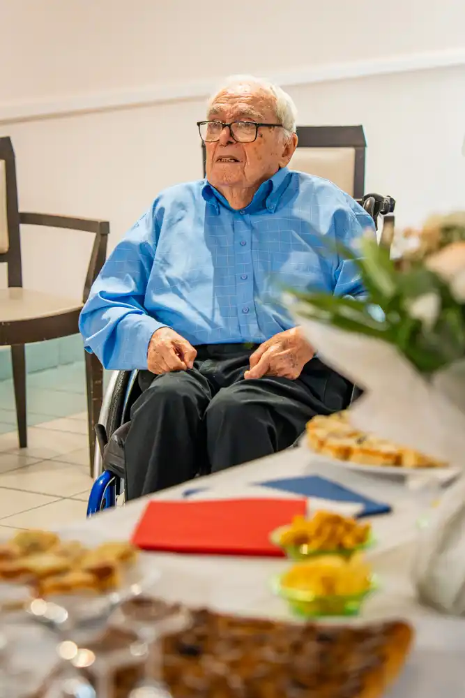 Albert Donnat assis dans un fauteuil roulant lors de la réception organisée pour sa remise de la Légion d’honneur.