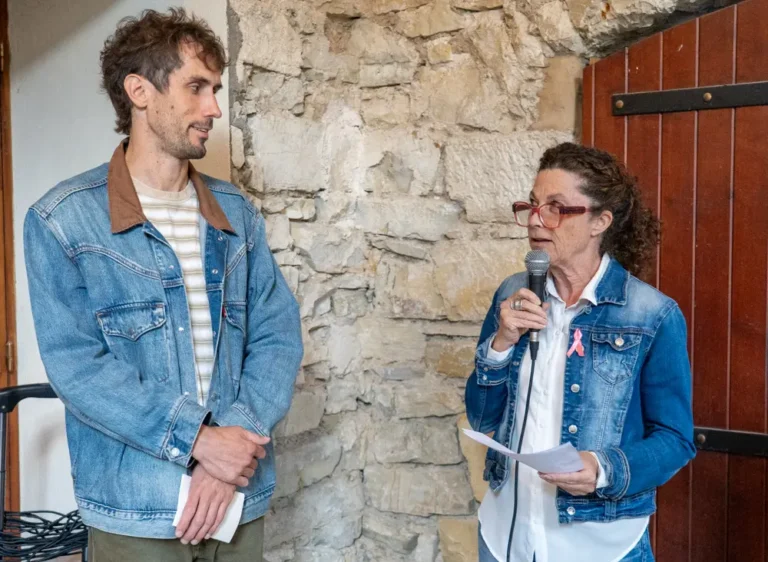 L'artiste Alex Mullen écoutant une intervenante prendre la parole au micro lors du vernissage de l'exposition Goat Country à la Chapelle de l'Observance.