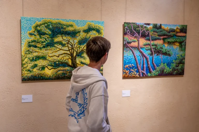Visiteur observant deux peintures paysagères aux couleurs vives lors de l'exposition Goat Country à la Chapelle de l'Observance.