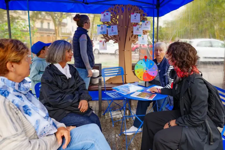 Bénévoles de l'Unafam accueillant le public sous un barnum bleu pour une action de sensibilisation à la santé mentale avec un arbre d'information et une roue de la fortune.