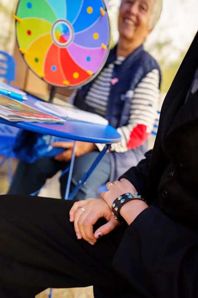 Une personne assise à une table bleue avec une roue de la fortune colorée, lors d'une action de sensibilisation de l'Unafam.